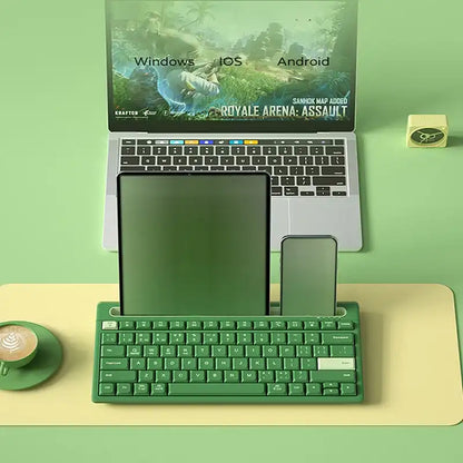 Green keyboard on a desk with a laptop displaying multiple operating system logos.