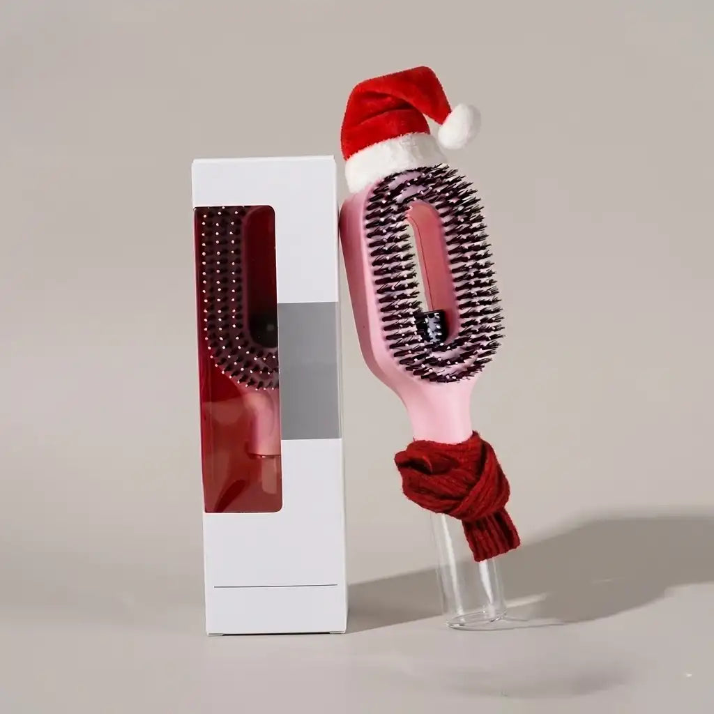 Hairbrush with a Santa hat and red scarf in front of a white box on a light gray background
