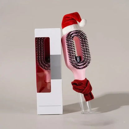 Hairbrush with a Santa hat and red scarf in front of a white box on a light gray background