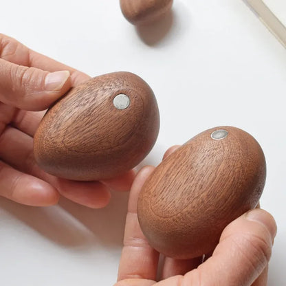 Hand balancing wooden stones with a hand holding one, on a light background