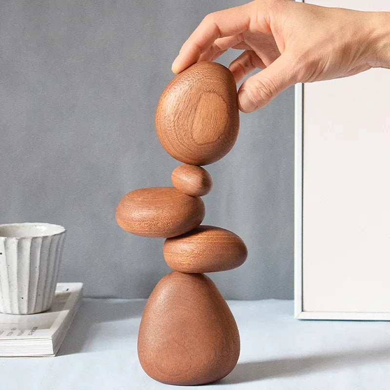 Hand balancing wooden stones on a gray background