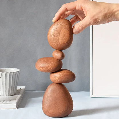Hand balancing wooden stones on a gray background