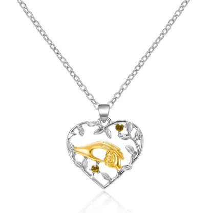 Heart-shaped pendant with gold fish design on a silver chain against a white background