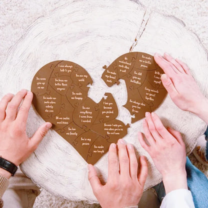 Heart-shaped puzzle with engraved text held by hands against a textured white background