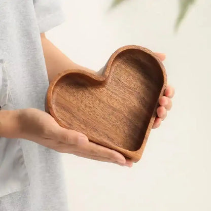 Heart-shaped wooden dish held by a person against a neutral background