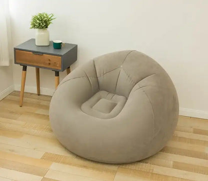 Inflatable beige chair on a wooden floor with a small table in the background.