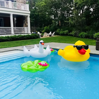 Inflatable swan, duck, and lily pad in a pool with a house and garden in the background.
