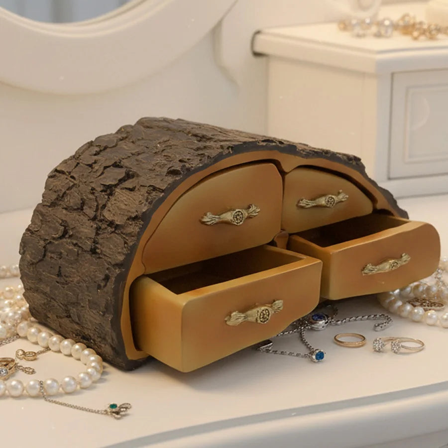 Jewelry box designed like a tree trunk with open drawers, surrounded by jewelry on a light surface.