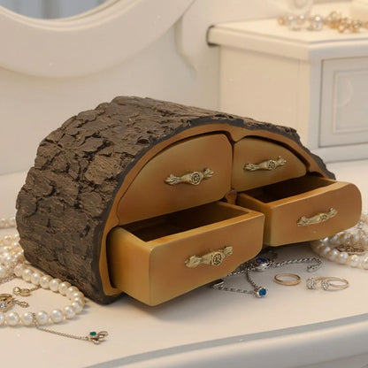 Jewelry box designed like a tree trunk with open drawers, surrounded by jewelry on a light surface.