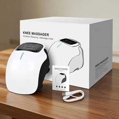 Knee massager with packaging, USB cable, and instruction sheet on a wooden surface.