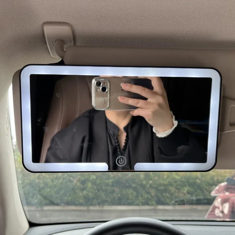 Car mirror with screen displaying a person taking a selfie.