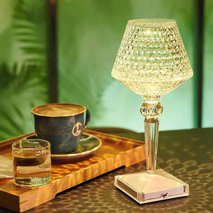Decorative table lamp with a glass shade on a wooden tray with a cup and glass.