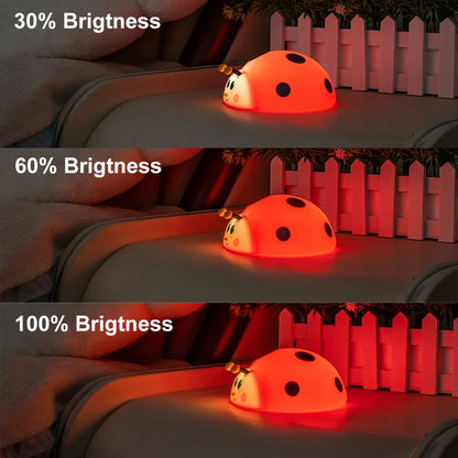 Three views of a ladybug-shaped night light with different brightness levels on a wooden surface.