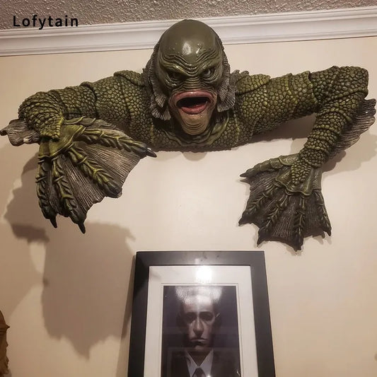 Green lizard-like creature wall decoration above a framed picture on a wall.