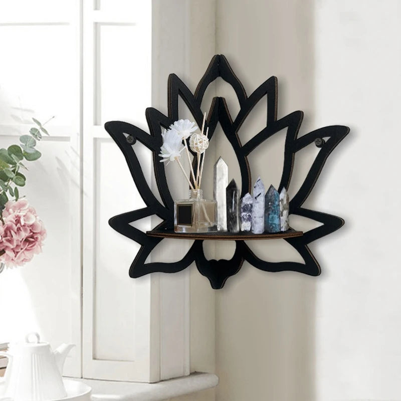 Decorative black wall shelf with crystals and flowers on a white wall.
