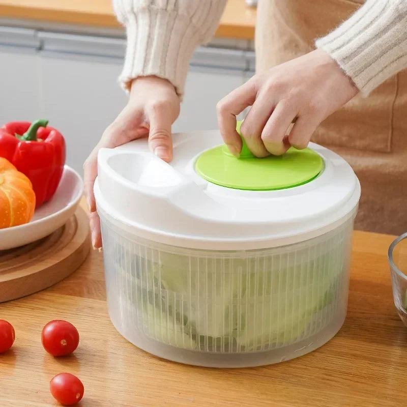 Person using a salad spinner with vegetables on a wooden table
