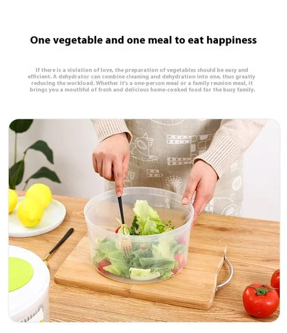 Person preparing salad with a salad spinner on a wooden table, surrounded by vegetables.