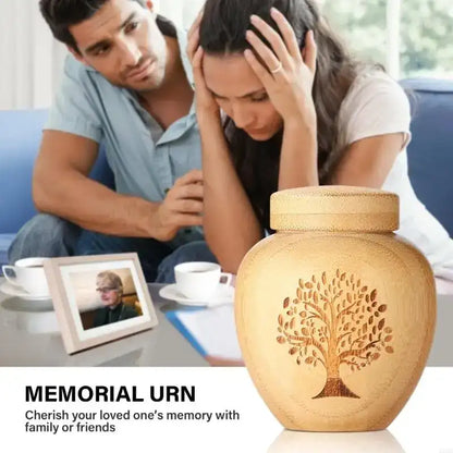 Memorial urn with a tree design on a table, with a couple sitting nearby.