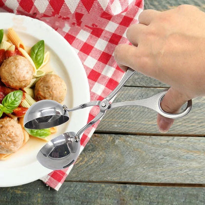 Metal tongs being used over a plate of pasta and meatballs on a checkered tablecloth.