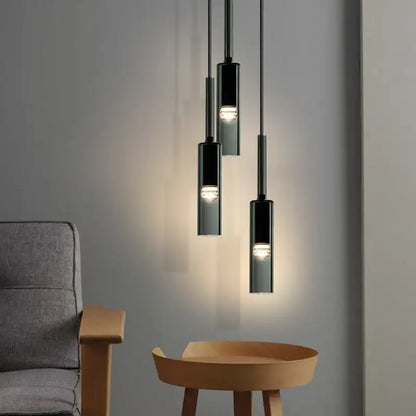Modern pendant lights hanging above a wooden table and gray sofa against a gray wall.