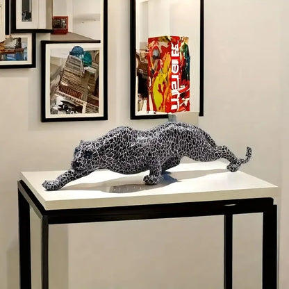 Metallic leopard sculpture on a table with framed artwork in the background