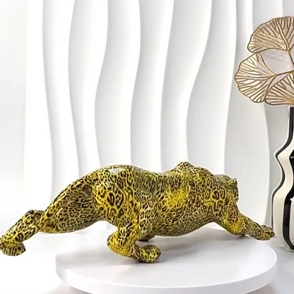 Yellow leopard figurine on a white pedestal with a white curtain and decorative vase in the background