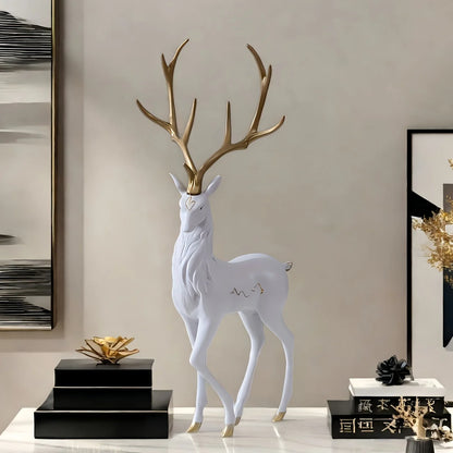 Decorative deer figure with gold antlers on a black pedestal against a neutral wall.
