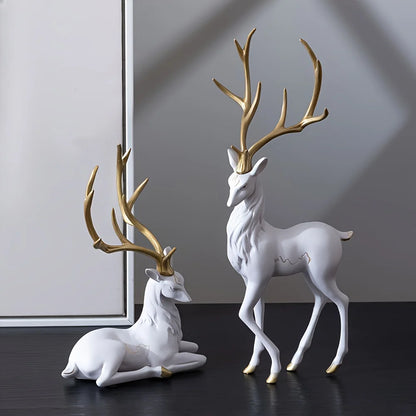 Two white Modern Deer Sculpture Set with gold antlers on a dark surface.