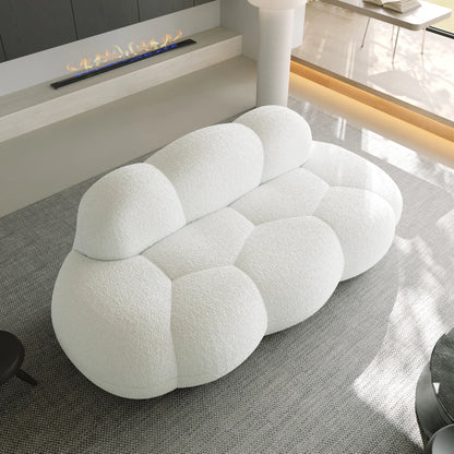 Modern white sofa in a living room setting with a fireplace and glass coffee table.