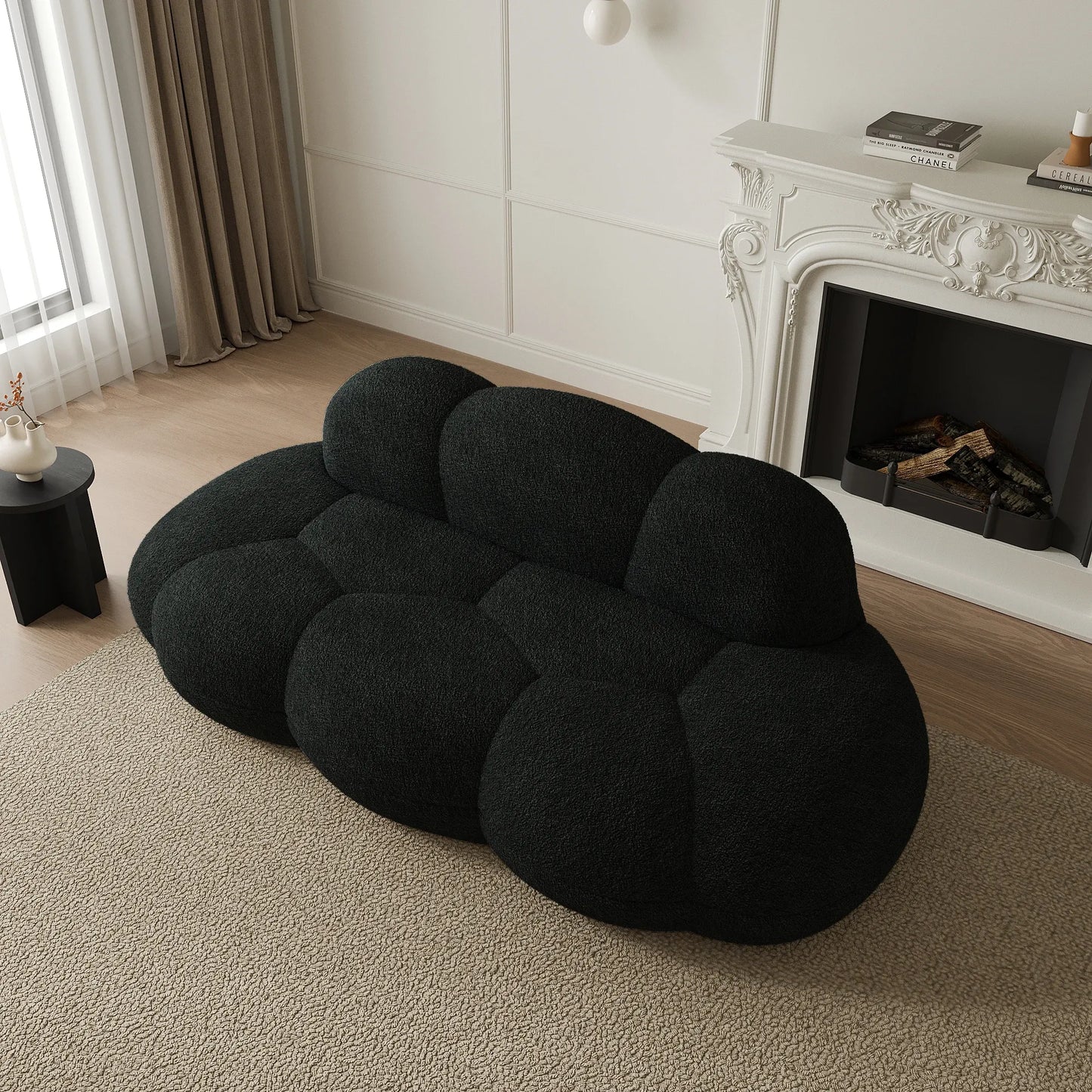 Black cloud-shaped sofa in a living room with a fireplace.