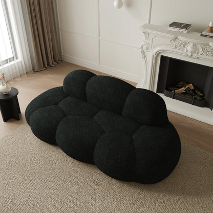 Black cloud-shaped sofa in a living room with a fireplace.