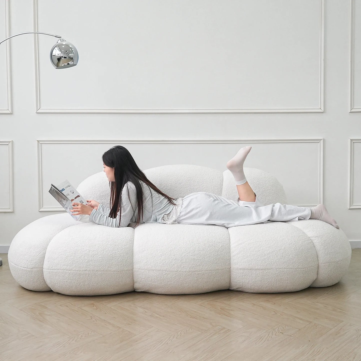 Person lying on a modern white bean bag chair in a minimalistic room.
