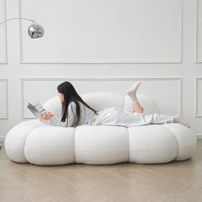 Person lying on a modern white bean bag chair in a minimalistic room.