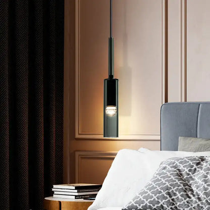 Modern pendant light fixture in a bedroom setting with a bed and books.