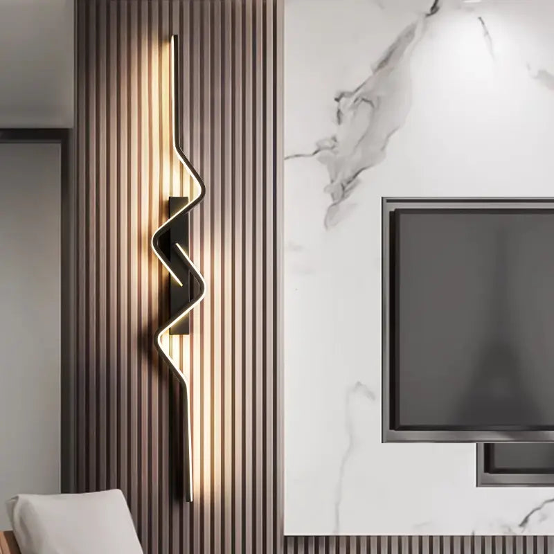 Modern wall sconce with a decorative design on a striped wall next to a television.