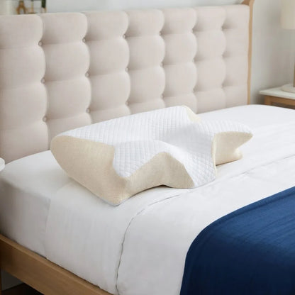 Neck pillow on a bed with a tufted headboard