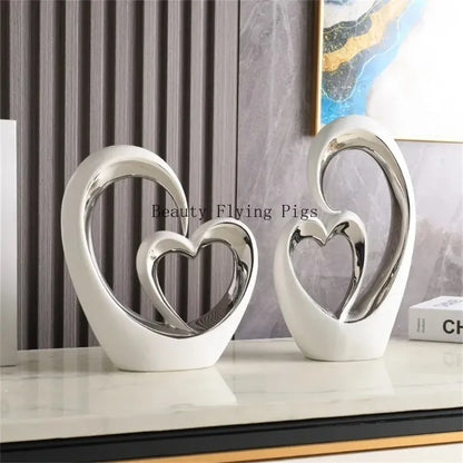 Two silver heart-shaped decorative pieces on a surface with a blurred background