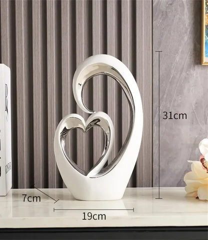 Decorative sculpture of two interlocking hearts with measurements on a marble surface.