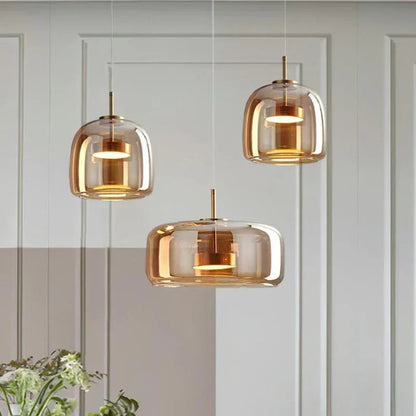 Three modern pendant lights hanging against a light gray wall.