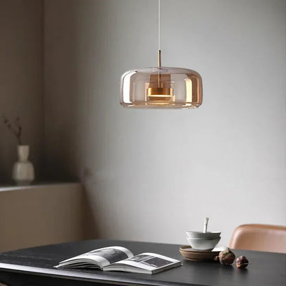 Modern pendant light hanging above a table with an open book and a bowl.