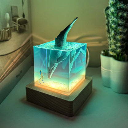 Decorative lamp with a dragon design on a wooden base, surrounded by a plant and a shelf in the background.