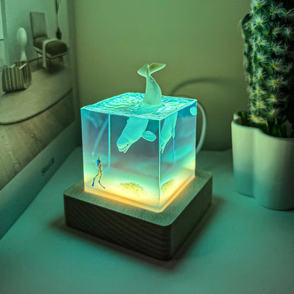 Glowing decorative lamp with mermaid and fish design on a table.