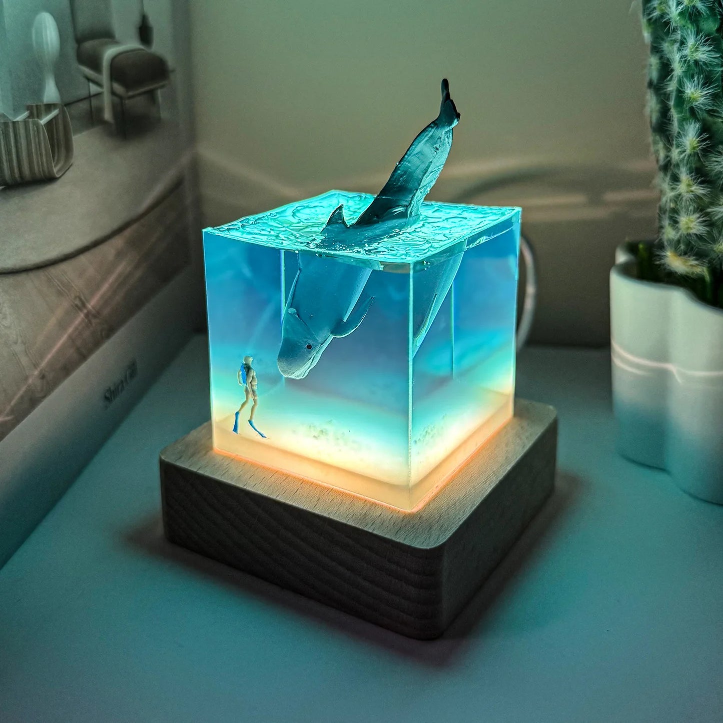 Decorative lamp with shark design on a wooden base, glowing in a room setting.