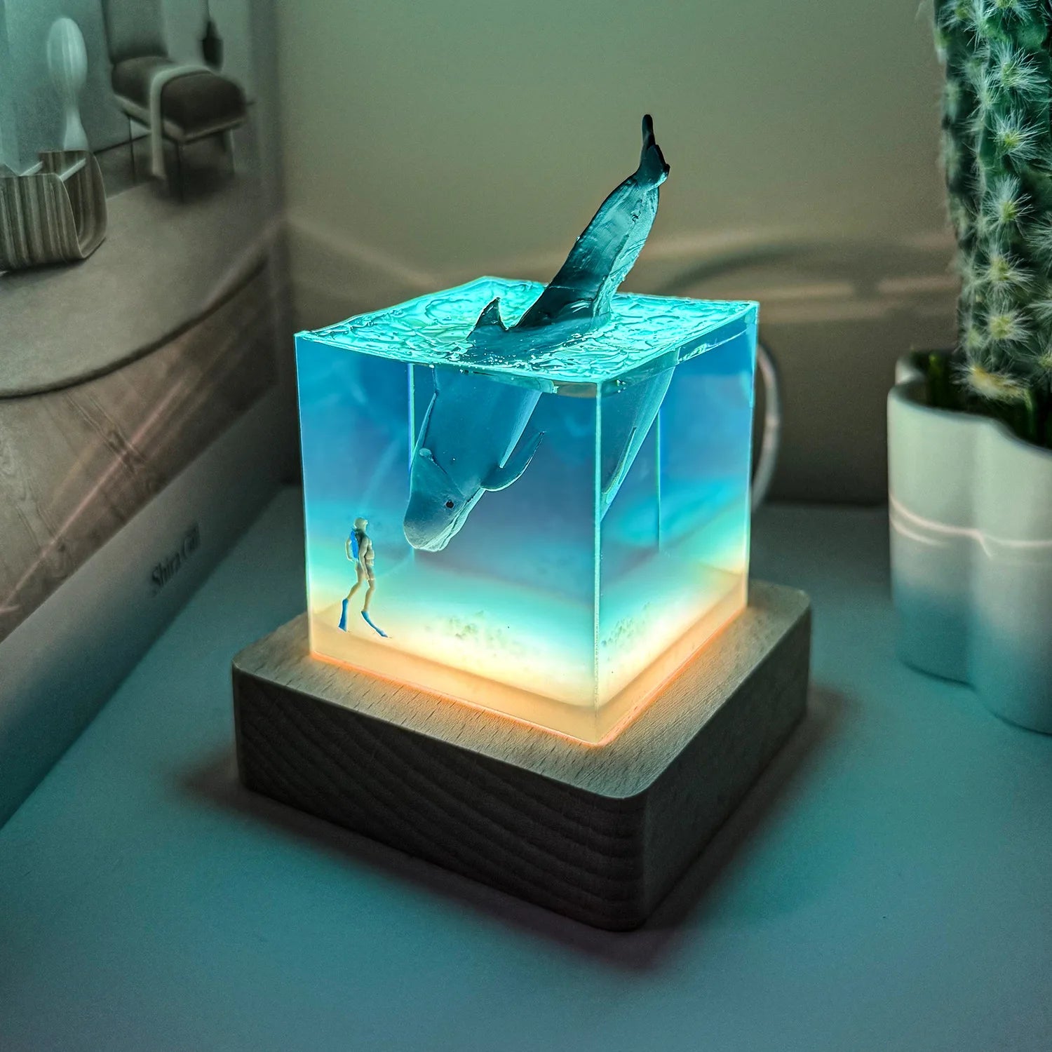 Decorative lamp with shark design on a wooden base, glowing in a room setting.