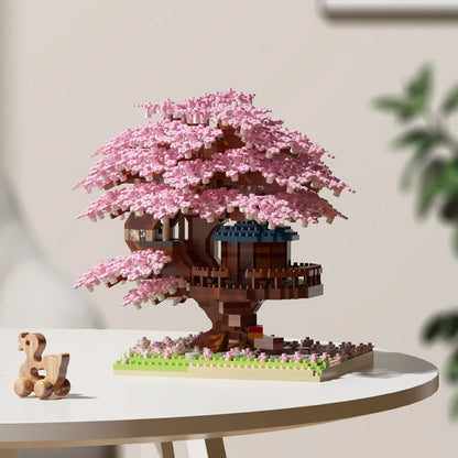 LEGO model of a cherry blossom tree with a small house on a table.