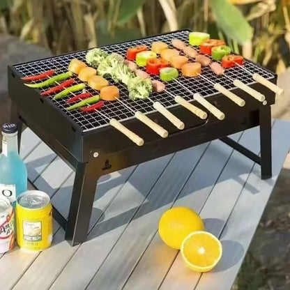 Portable grill with skewered vegetables on a wooden deck, surrounded by drinks and oranges.