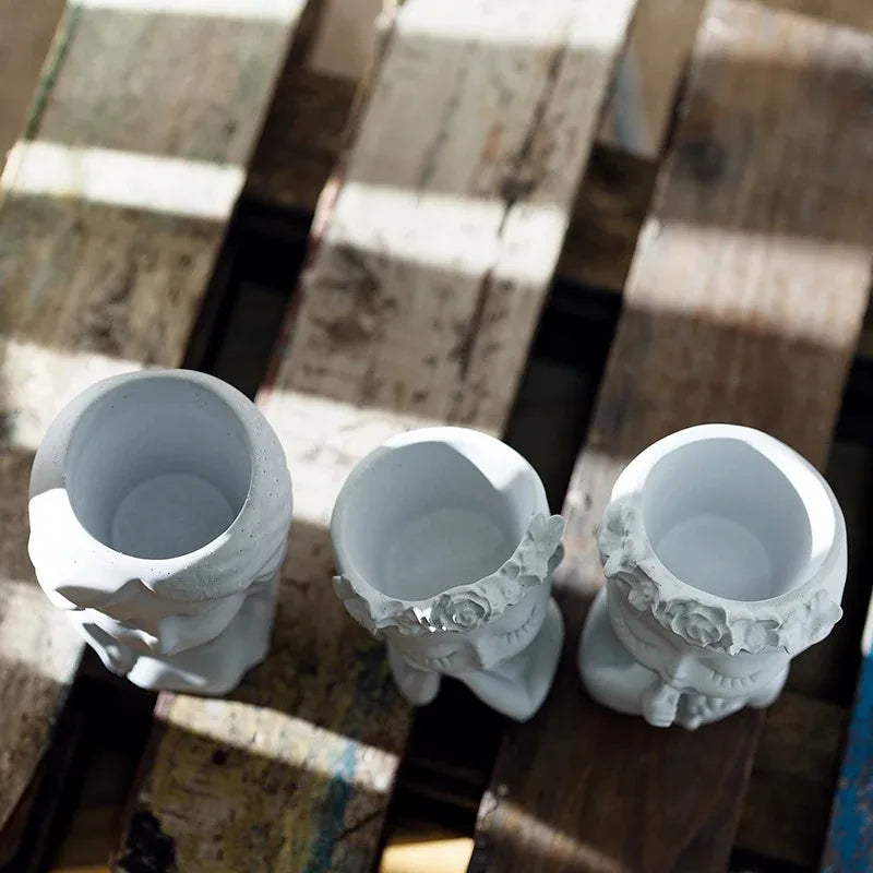 Three white ceramic planters with decorative designs on a wooden surface