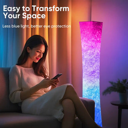 Woman sitting on a couch using a phone with a tall, olcorful floor lamp in the background.
