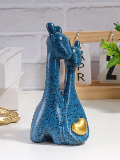 Blue ceramic giraffe figurine with a gold heart on a white surface.