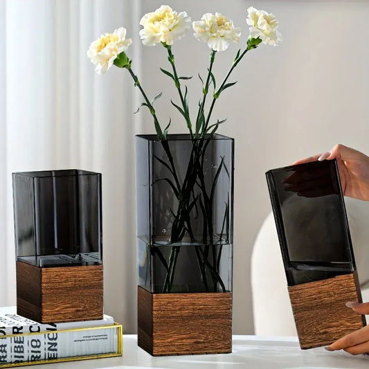Set of three decorative vases with wooden base and glass top, one being held by a hand.